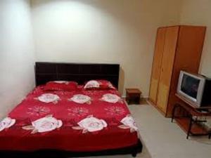 a bedroom with a red bed and a television at OYO 90842 Hotel Prai Jaya in Perai