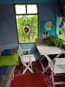 Zimmer mit einem Tisch, einer Bank und einem Fenster in der Unterkunft Baanchaokoh Homestay in Kanchanaburi