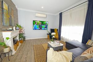 sala de estar con sofá y TV en Fawkner Modern 3BR House Netflix WiFi Parking, en Melbourne