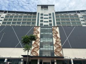a tall building with a palm tree in front of it at SUMMER SUITES APARTMENT-The Summer Shopping Mall in Kota Samarahan