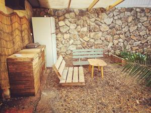 un banco de madera sentado frente a una pared de piedra en יחידת אירוח גלילית en Hatzor haglilit