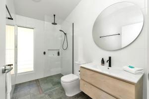 Un baño blanco con inodoro y espejo. en Treehaven Hyams Beach, en Hyams Beach 15 fotos más