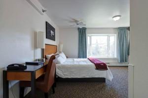 a bedroom with a bed and a desk and a window at Puffin Inn in Anchorage