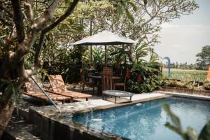 a pool with a table and an umbrella and chairs at Mandala Desa in Sukawati