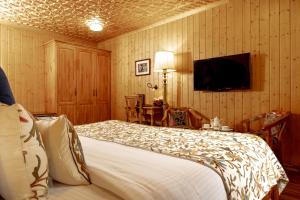 a bedroom with a bed and a tv on the wall at Shaw Inn by Stay Pattern in Gulmarg