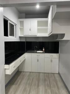 a white kitchen with white cabinets and a sink at The Grey House in Bacong
