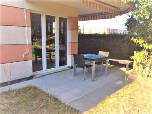 un patio con una mesa y un banco junto a una casa en Apartment with Garden in Nyon en Nyon