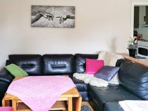 una sala de estar con un sofá de cuero negro con almohadas coloridas en Two-Bedroom Holiday home in Digermulen, en Digermulen