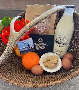 a basket filled with food and a bottle of milk at Fridas Accommodation in Raglan