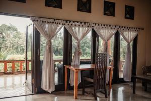 a table and chairs in a room with windows at Mandala Desa in Sukawati