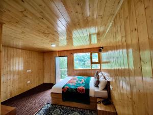 1 dormitorio con 1 cama en una pared de madera en Apple Valley Cottages Lachung en Lachung