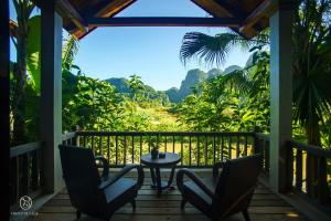 a porch with two chairs and a table and a view at Nham Village Resort in Ninh Binh