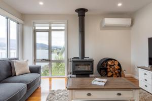 a living room with a couch and a wood stove at Derwent River Cottage - Tranquil Waterfront Living in Goodwood