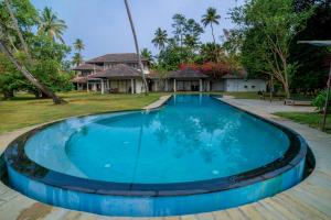 a large blue pool in front of a house at Cranganor History Café & Riverside Château in Parūr