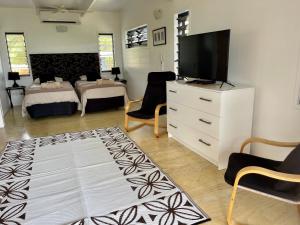 a living room with a tv and a bedroom at Rarotonga Villas Absolute Beachfront in Arorangi
