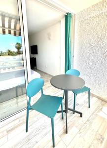 twee blauwe stoelen en een tafel in een kamer met een raam bij Borinquen Vista Mar in Playa de las Americas