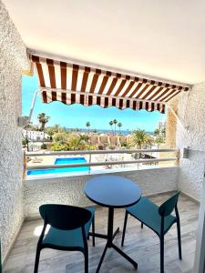 a table and chairs on a balcony with a view of a pool at Borinquen Vista Mar in Playa de las Americas