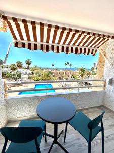 d'une table et de chaises sur un balcon avec vue sur la piscine. dans l'établissement Borinquen Vista Mar, à Playa de las Americas