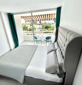 a bedroom with a bed and a balcony with a table at Borinquen Vista Mar in Playa de las Americas