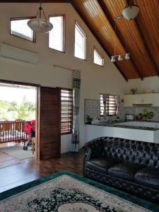 a living room with a black leather couch and a wooden ceiling at Fiji-Beauty in Nadi