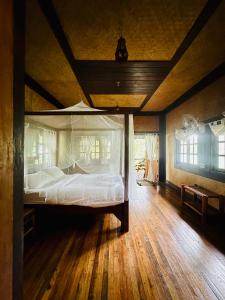 Cama grande en habitación con suelo de madera en Bambu Huts en Baan Tai