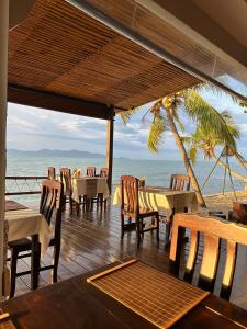 a restaurant with tables and chairs on the beach at Adarin Beach Resort in Mae Nam