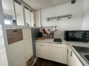 a kitchen with white cabinets and a microwave at Studio hyper centre Pornichet in Pornichet +1 photo
