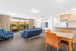 uma sala de estar com um sofá azul e uma mesa e cadeiras em APX Parramatta em Sidney