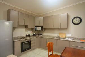 a kitchen with white cabinets and a clock on the wall at Kangelani Lodge in Hillcrest