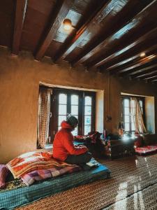 een persoon op een bed in een kamer bij Zomsa Culturehub in Kyelang