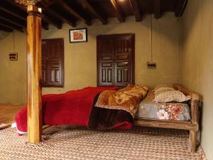 a bedroom with a bed with a red comforter at Zomsa Culturehub in Kyelang