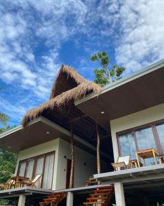 ein Haus mit Stühlen und einem Strohdach in der Unterkunft Island Casitas Siquijor in Siquijor