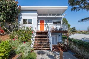 a white house with an orange door and stairs at Sunset Cottage - oceanstays in Yamba