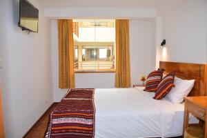 a bedroom with a bed and a window at Hotel Inka Pisac in Pisac