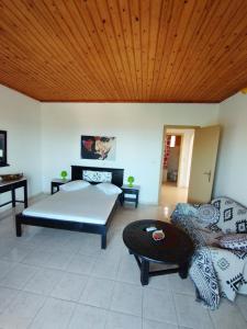 a bedroom with a bed and a couch and a wooden ceiling at spasmata houses in Minia