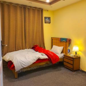 a bedroom with a bed with a red blanket on it at Ringchan Guest House & Restaurant in Skardu