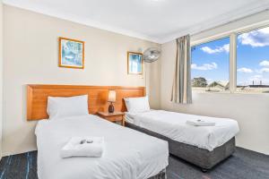 two beds in a room with a window at APX Parramatta in Sydney