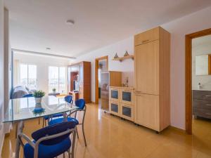 a kitchen with a glass table and blue chairs at Mahostly Corralejo Vista Mar in Corralejo
