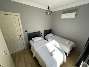 two beds in a room with white sheets at Tas Homes Antalya in Antalya