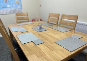 una mesa de madera con 4 sillas y esterillas. en 3 Bedroom Apartment, Ballymena, The Wee Stop Gap, en Ballymena