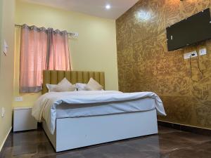 een slaapkamer met een bed en een flatscreen-tv bij Skylight homestay in Dehradun