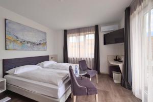 une chambre d'hôtel avec un lit, une table et des chaises dans l'établissement Hotel Luna Garni, à Ascona