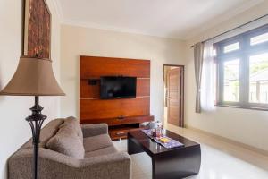 a living room with a couch and a tv at Jenna Residence Denpasar in Denpasar