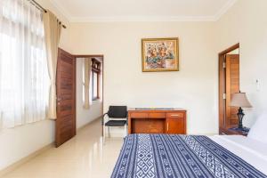 a bedroom with a bed and a desk and a chair at Jenna Residence Denpasar in Denpasar