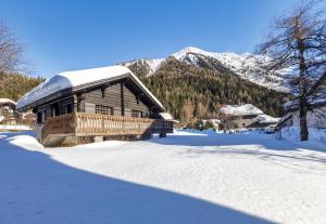 a log cabin in the snow with mountains in the background at Chalet Spouter Happy Rentals in Chamonix