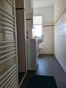 uma casa de banho com um lavatório, um WC e uma janela. em Gästewohnung KL. WZL 38_5 