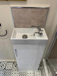 a white sink in a bathroom with a tile floor at No 1 Hut Lane, a cosy Hut, heating, hot water and a magnificent view for 2 in Dorchester