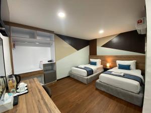 a hotel room with two beds and a table at Assalam Hotel in Kota Bharu
