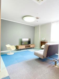 uma sala de estar com uma televisão, um sofá e uma cadeira em ROSE ROOM em Fukuyama