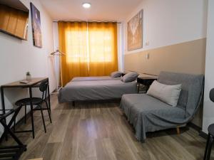 Habitación con 2 camas, mesa y silla en Alianza Suites en Madrid